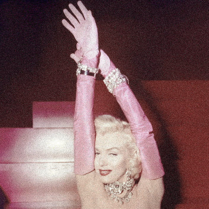 Vieille photo de Marilyn Monroe levant les bras, avec des longs gants roses, et plein de bijoux