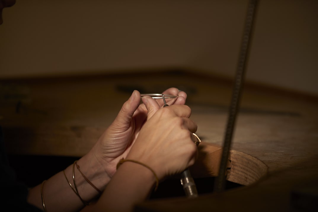 On voit les mains de la créatrice de bijoux Louise Vurpas en train de travailler sur un bracelet au-dessus de son établi. Bijouterie-joaillerie sur-mesure